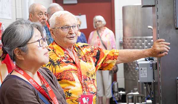Alumni participating in a guided campus tour, listening to a guide inside a campus facility during Alumni Reunion Weekend.